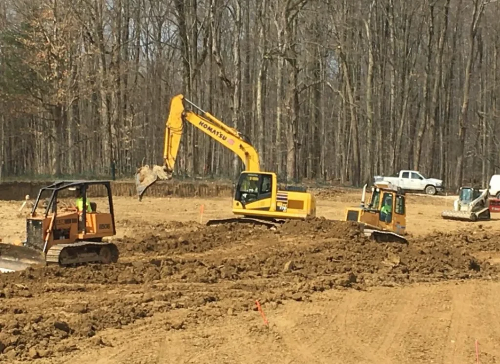 Excavators grading wooded lot